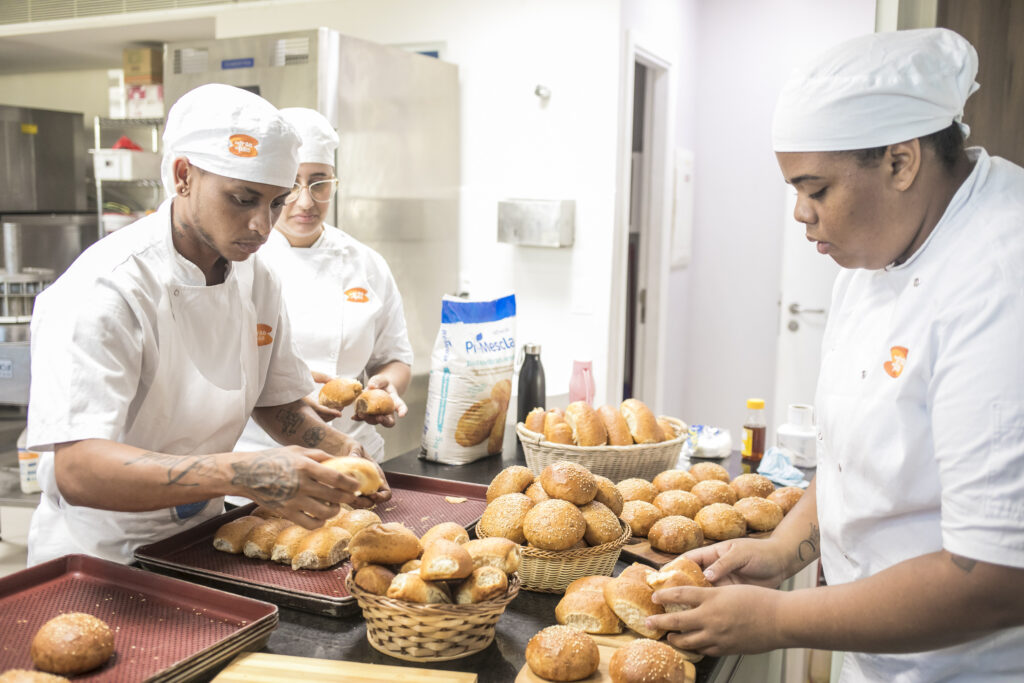tres pessoas preparando pães para assar