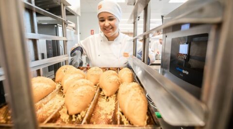 mulher com bandeja de pães saindo do forno