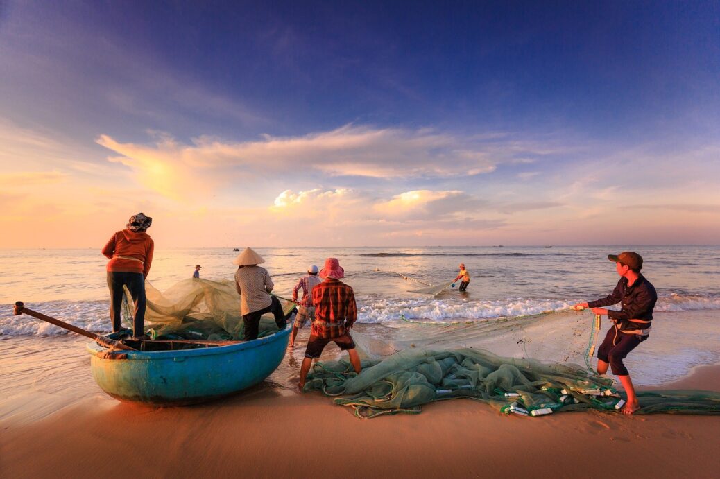 pequenos pescadores na praia puxando rede de pesca