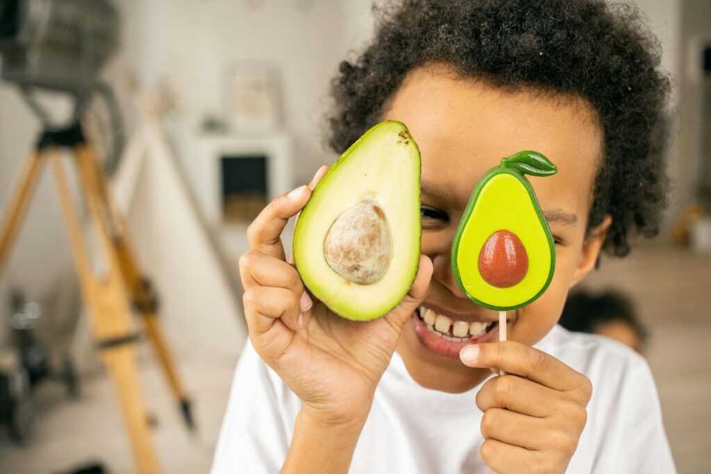 criança feliz e saudável com abacate na mão